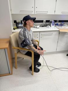 Olympic BMX star Kieran Reilly seated in a chair in a medical facility, wearing a blood pressure cuff.