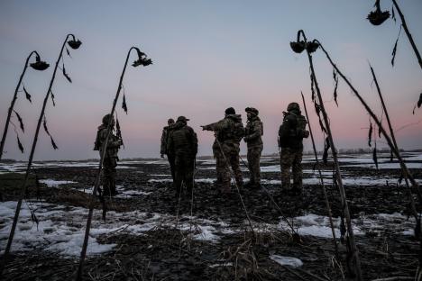 Ukrainian soldiers in a field after an air raid.
