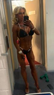 Woman in a competition bikini taking a selfie in a dressing room.