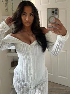 Woman in white off-the-shoulder dress taking a selfie.