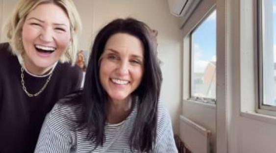 Two women smiling for a video.
