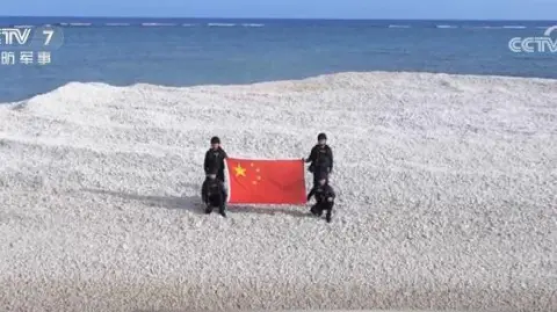 People holding Chinese flag on a small sandbank.