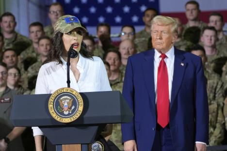 Gretchen Whitmer speaking at a podium with Donald Trump standing behind her.