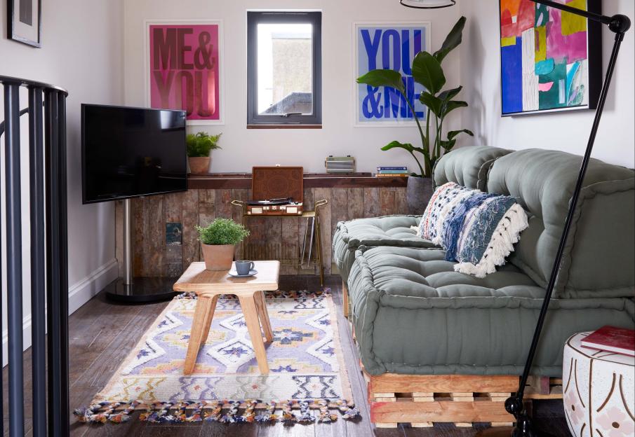 Living room with green sofa, rug, and artwork.
