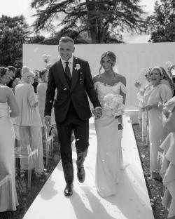 Black and white photo of Dani Dyer and Jarrod Bowen walking down the aisle after their wedding ceremony.
