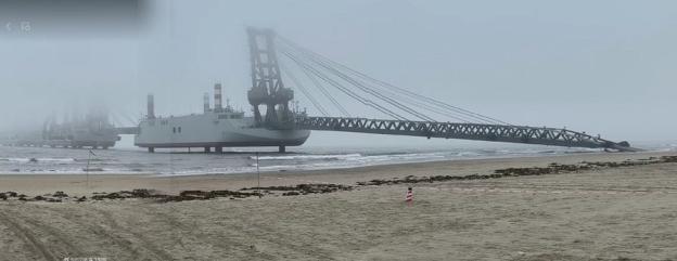 Large crane ship on the beach in foggy conditions.