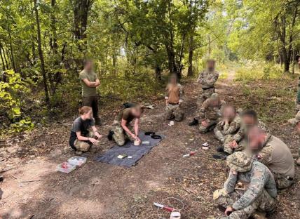 Ukrainian frontline medics receiving training in a wooded area.